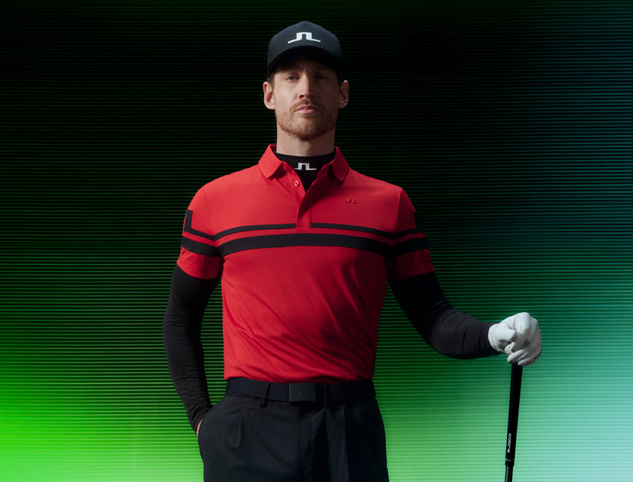 Man wearing a red and black golf outfit with a cap on a gradient green to black background