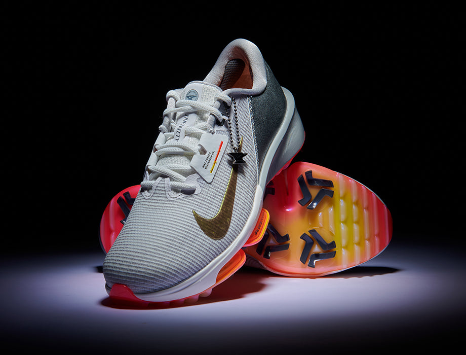 Grey nike golf shoe with colourful sole on a black background